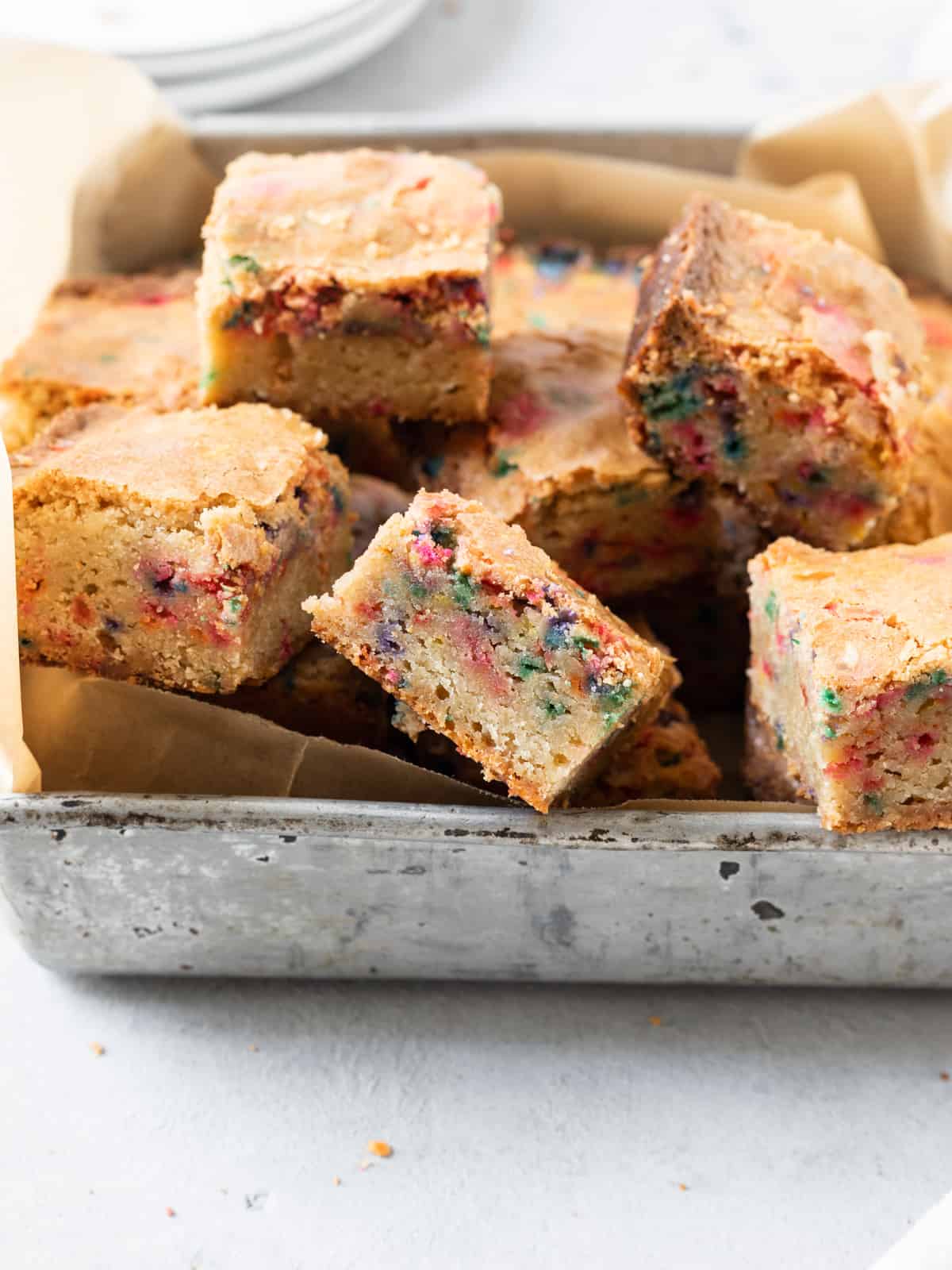 several funfetti blondies in a metal pan on a grey background.