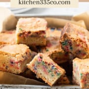 several funfetti blondies in a metal pan on a grey background. It says funfetti blondies across the top.