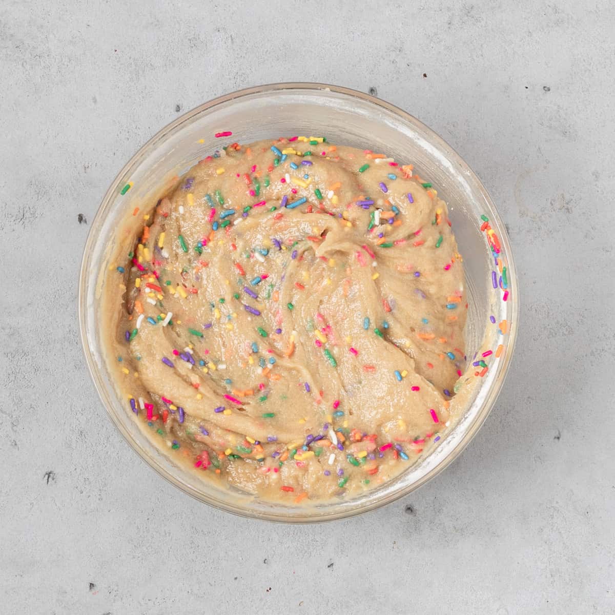 the completed blondie batter in a glass bowl on a grey background.