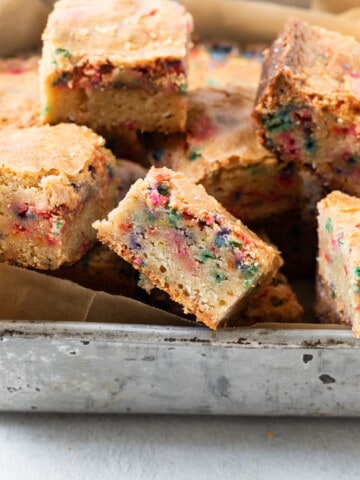 several funfetti blondies in a metal pan on a grey background.