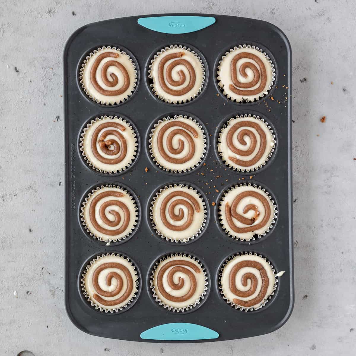 the mini cheesecakes prepared in a muffin tin before being baked.