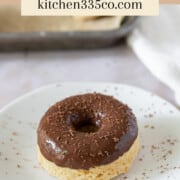 a chocolate glazed donut on a white plate that has been sprinkled with chocolate shavings. It says chocolate glazed donuts across the top.