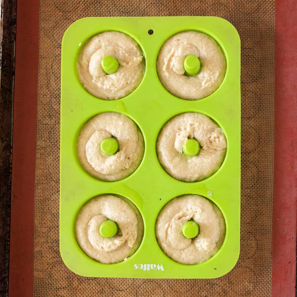 the donuts in a green donut pan before being baked.