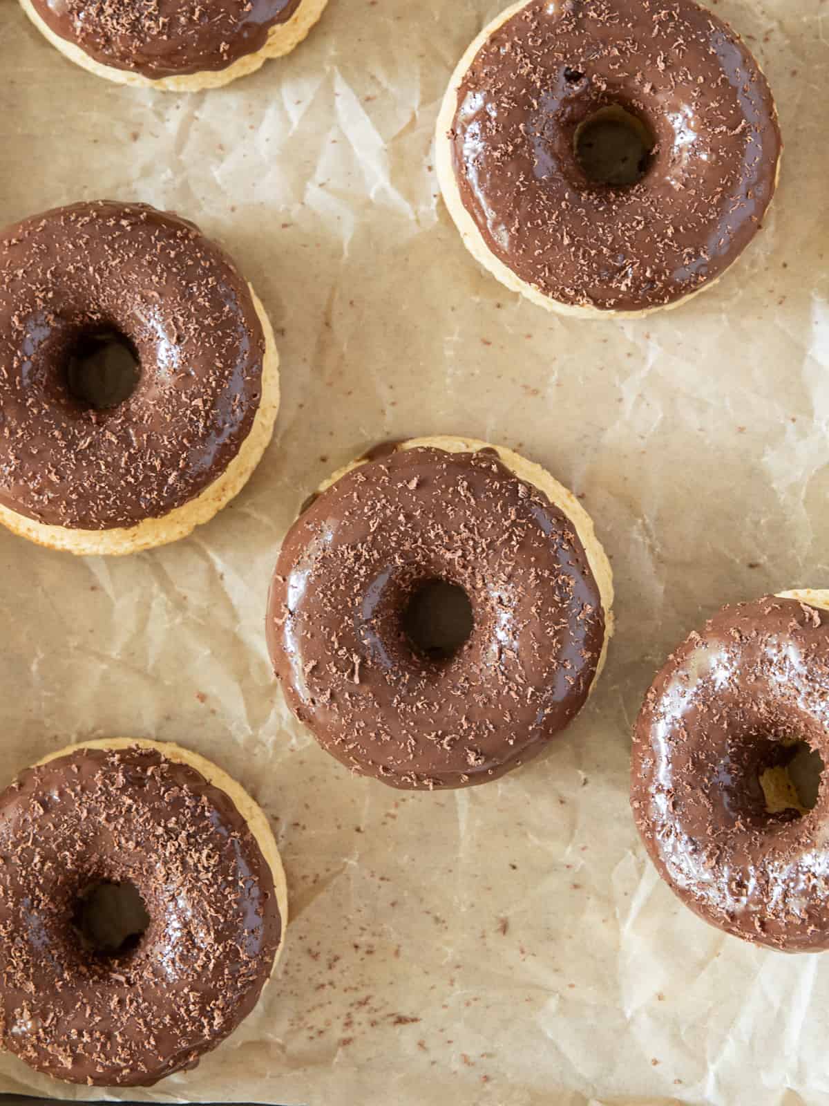 a platter full of chocolate glazed donuts topped with chocolate shavings.