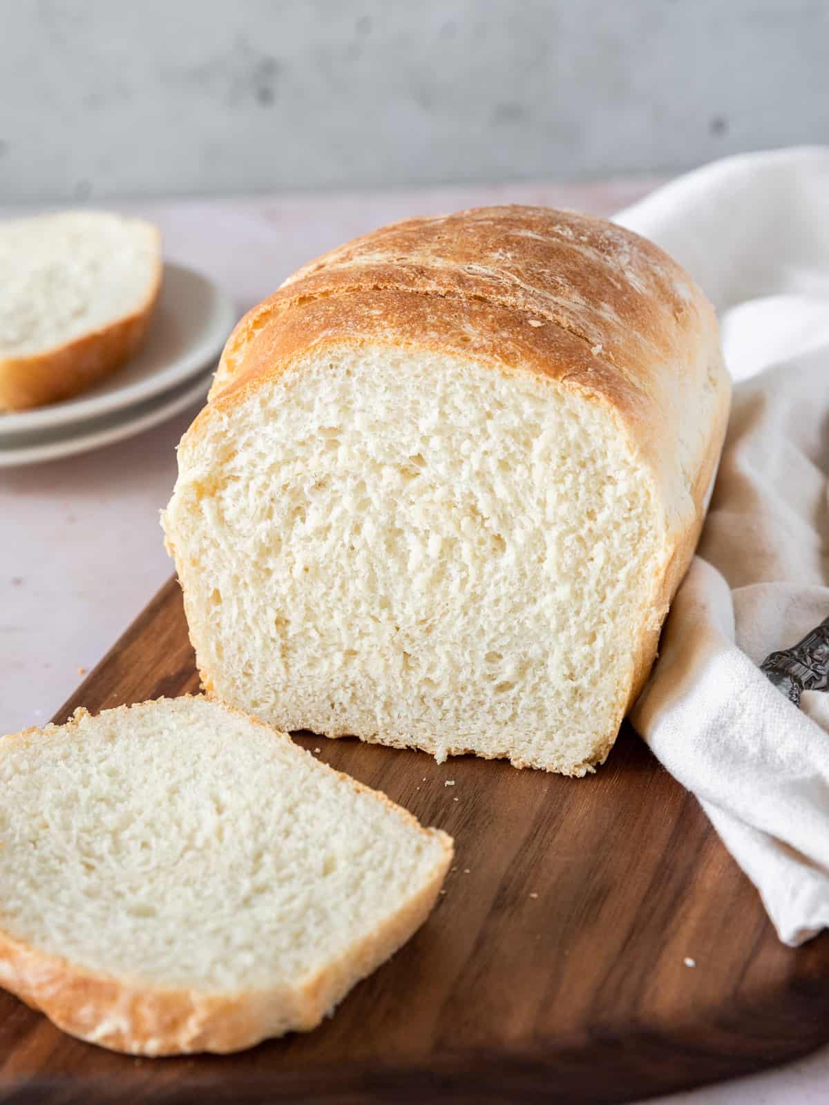 a loaf of white bread sliced up on a wooden cutting board.