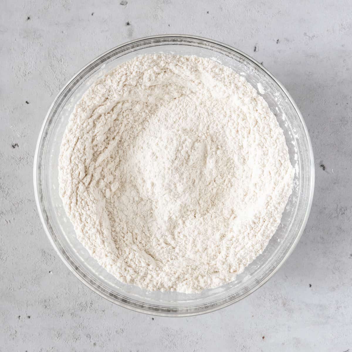 the flour and salt combined in a glass bowl on a grey background.