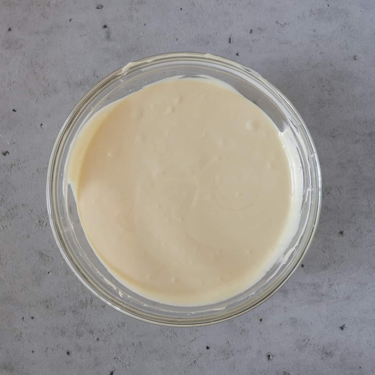 the completed cheesecake batter in a glass bowl on a grey background.