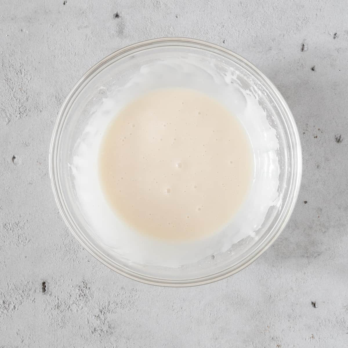 the vanilla glaze in a glass bowl on a grey background.