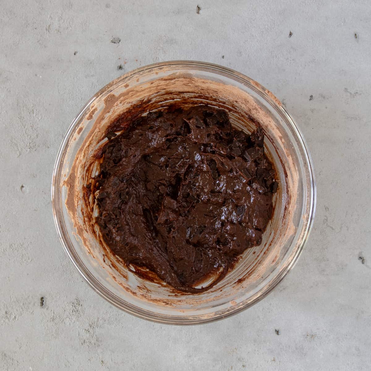 the completed brownie batter in a glass bowl on a grey background.