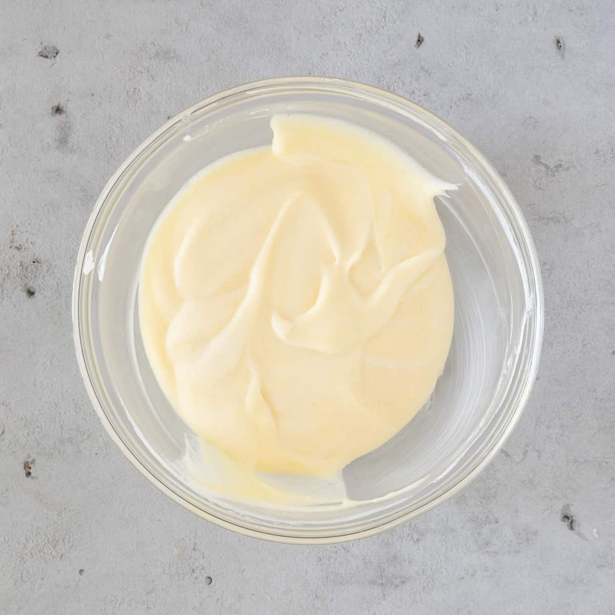 the whipped cream and lime curd combined in a glass bowl on a grey background.
