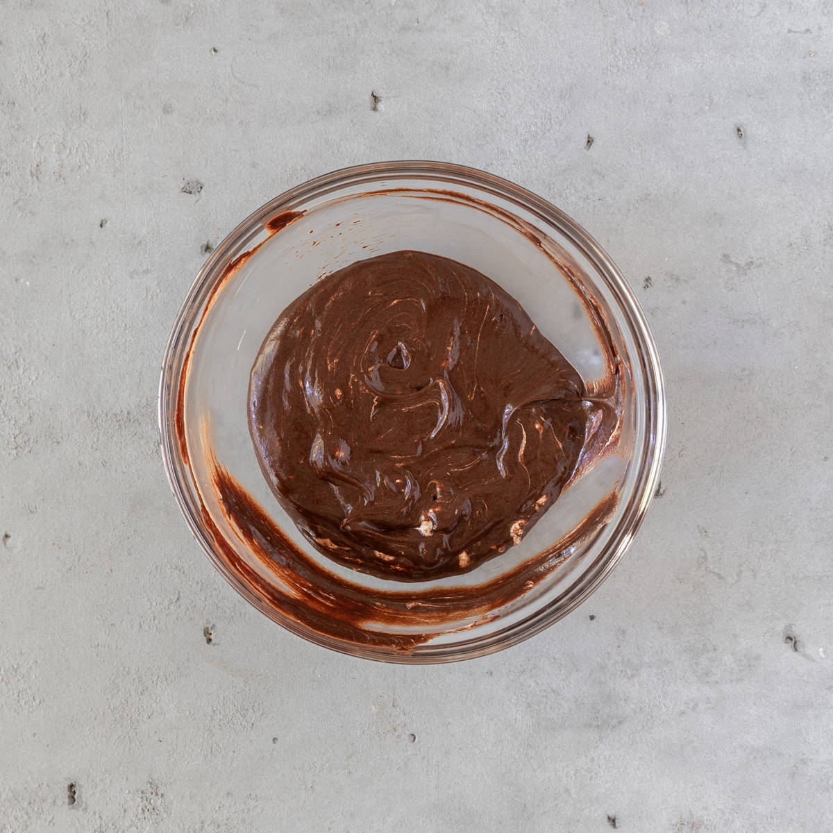 the chocolate and marshmallow ganache in a glass bowl on a grey background.