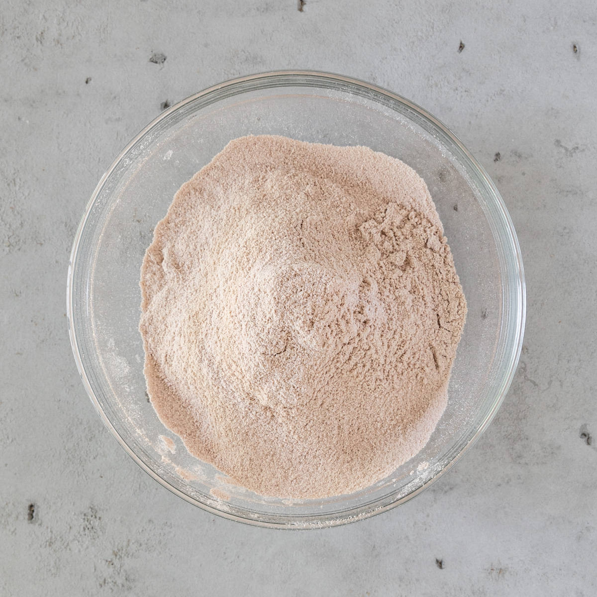 the dry ingredients sifted together in a glass bowl on a grey background.