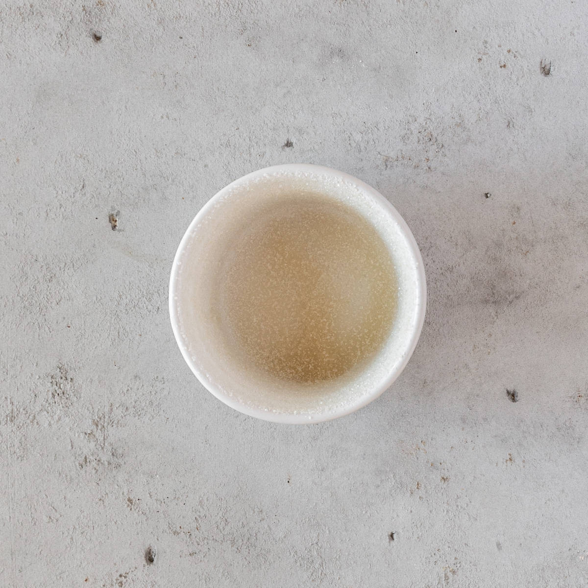 a ramekin that has been oiled and coated with sugar on a grey background.