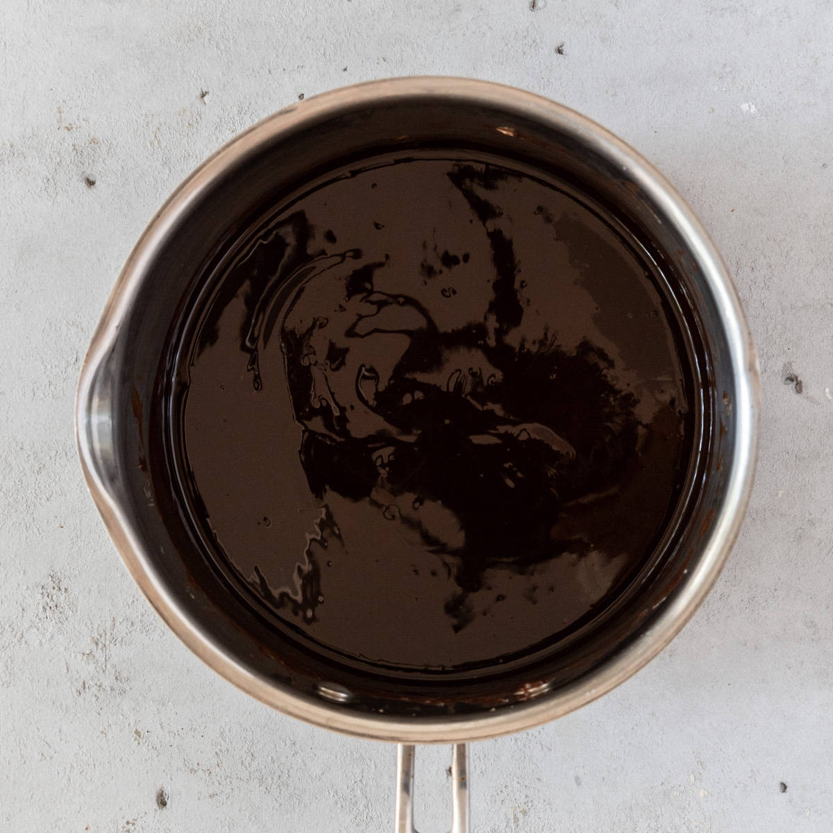 the butter and chocolate melted down in a saucepan on a grey background.