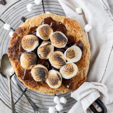 a peanut butter s'mores skillet cookie surrounded by mini marshmallows and chunks of chocolate.