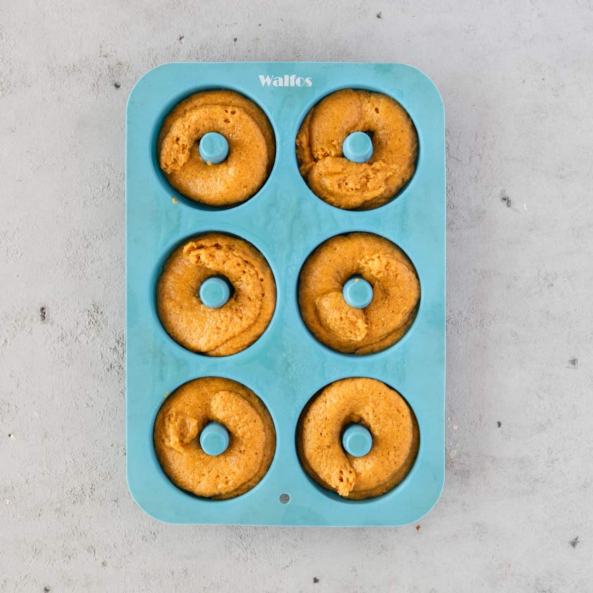 the pumpkin donut batter piped into a silicone donut mold before baking.