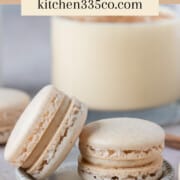 two eggnog macarons on a small dish surrounded by other macarons. It says eggnog macarons across the top.