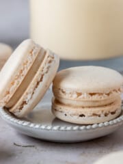 two eggnog macarons on a small dish surrounded by other macarons.