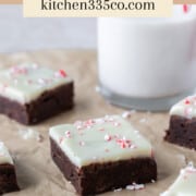 peppermint bark brownies on parchment paper with crushed up peppermints sprinkled around. It says peppermint bark brownies across the top.