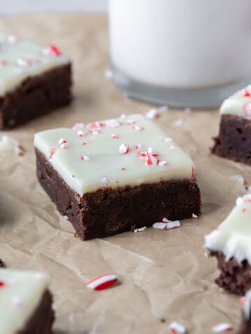 peppermint bark brownies on parchment paper with crushed up peppermints sprinkled around.