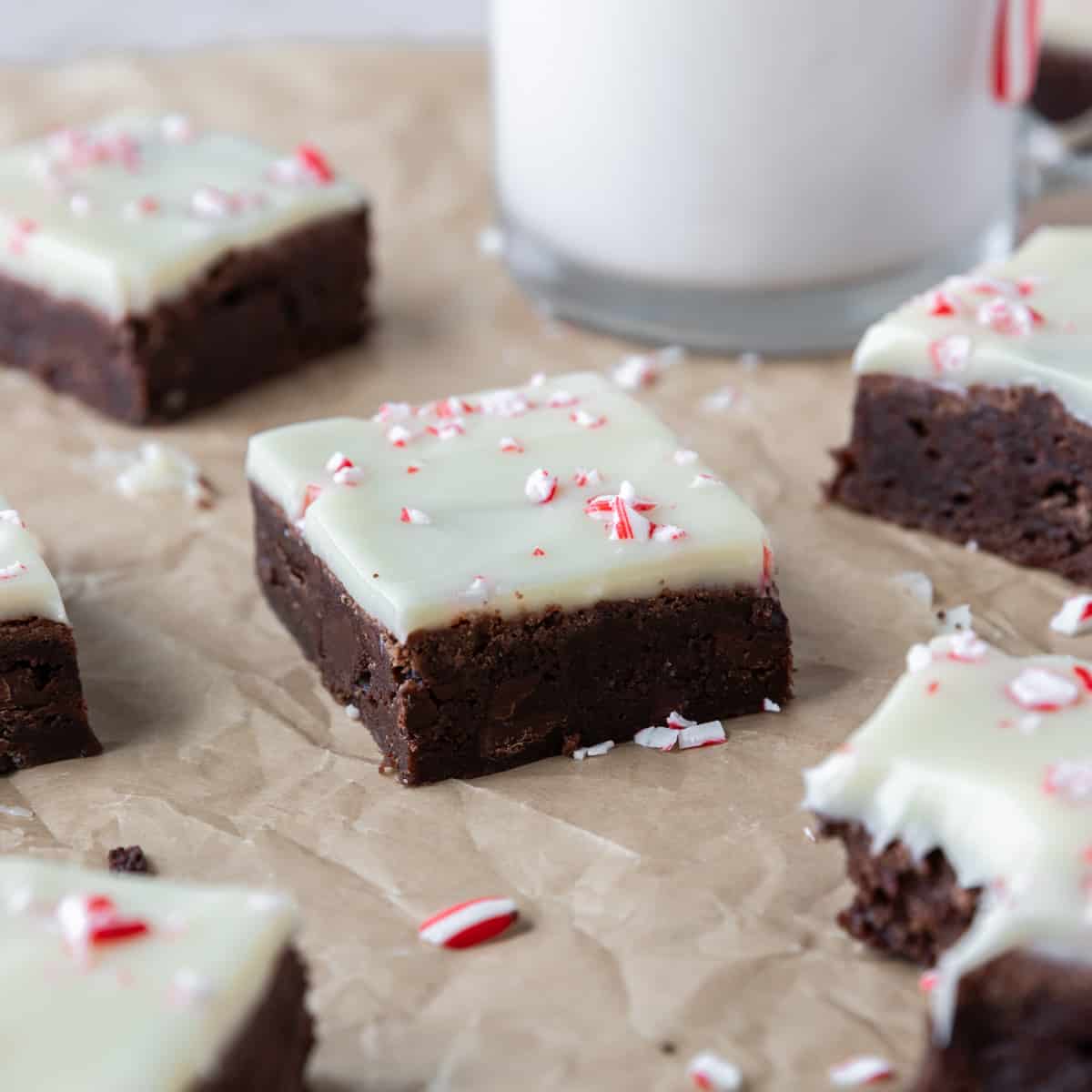 peppermint bark brownies on parchment paper with crushed up peppermints sprinkled around.