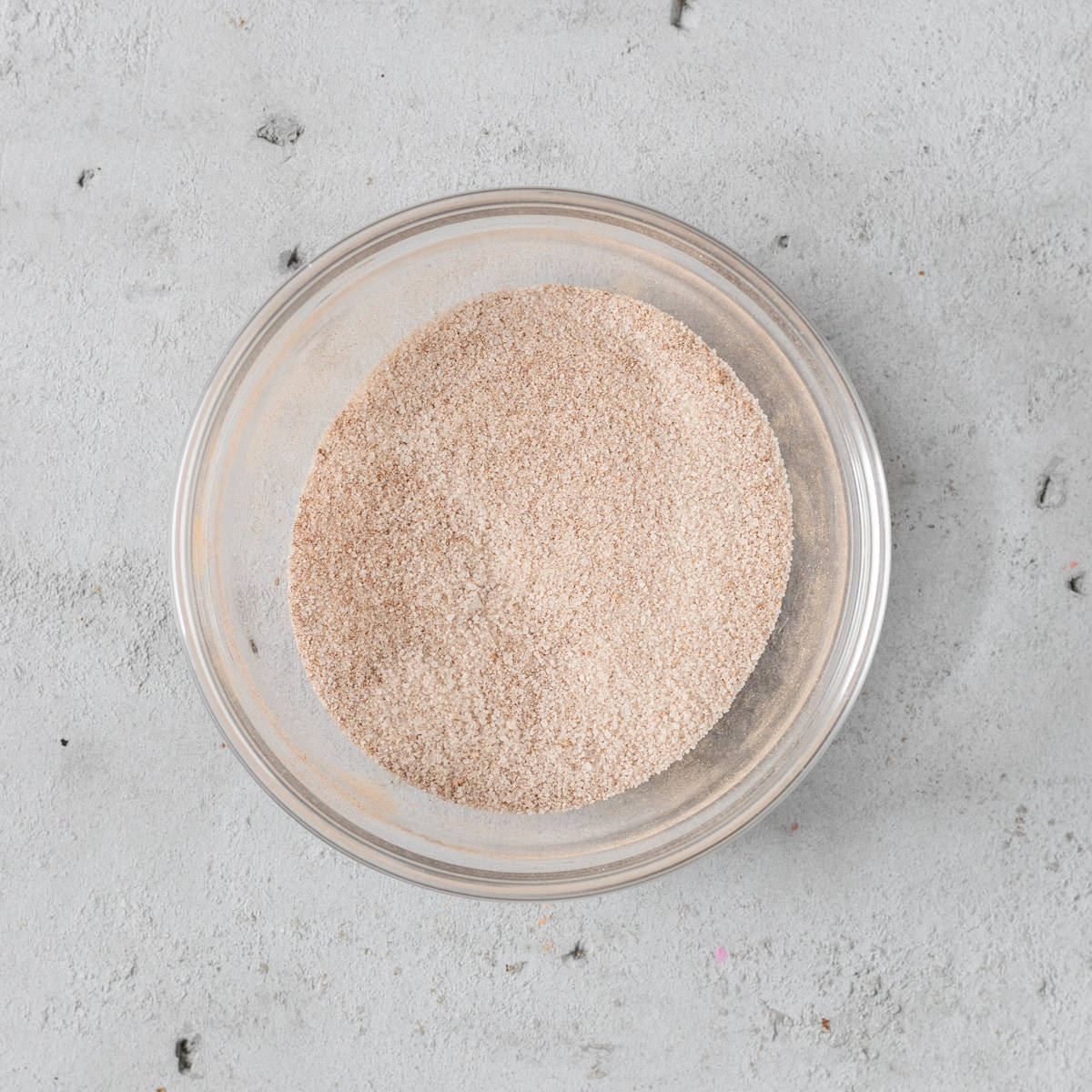 the cinnamon sugar mixture in a glass bowl on a grey background.