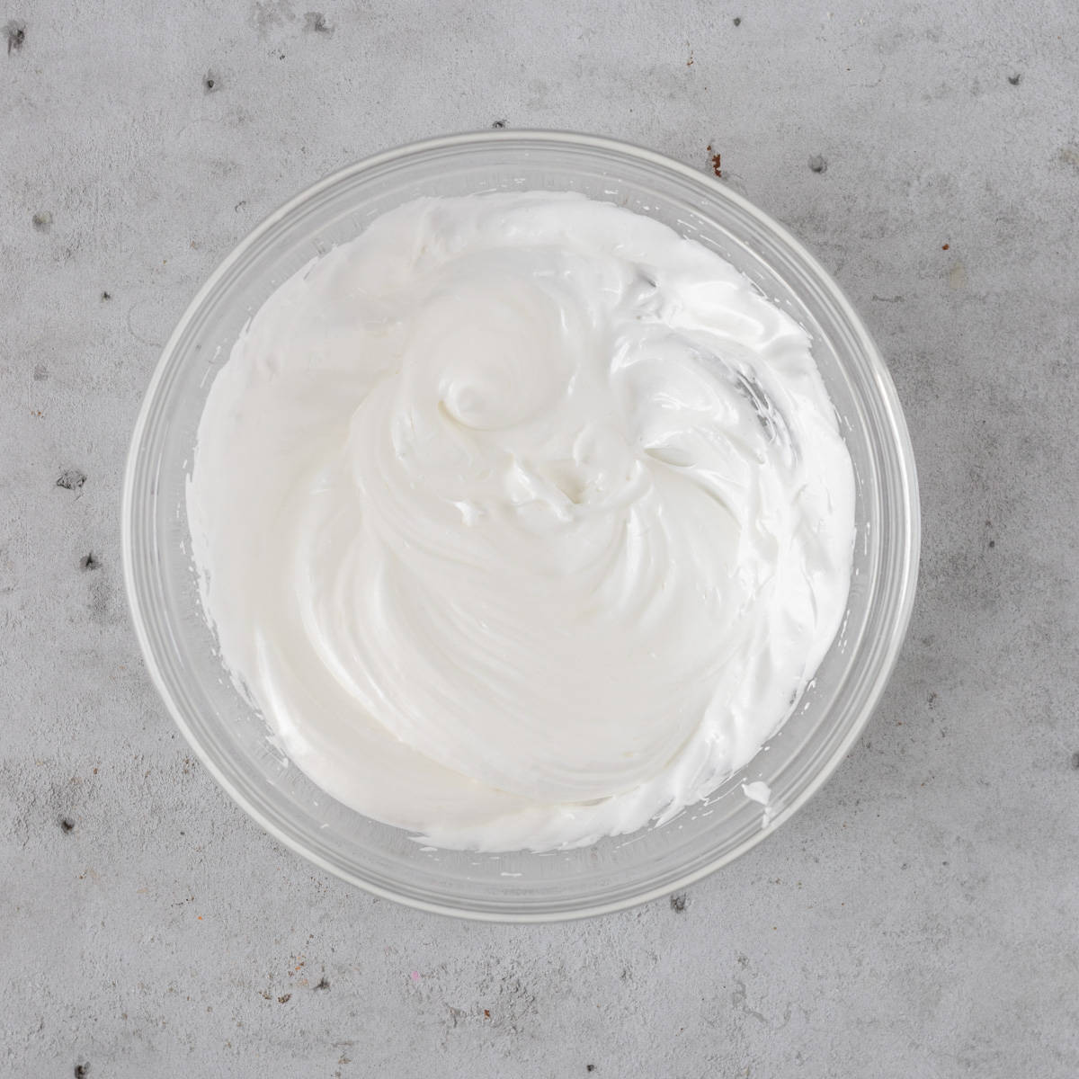 the french meringue in a glass bowl on a grey background.