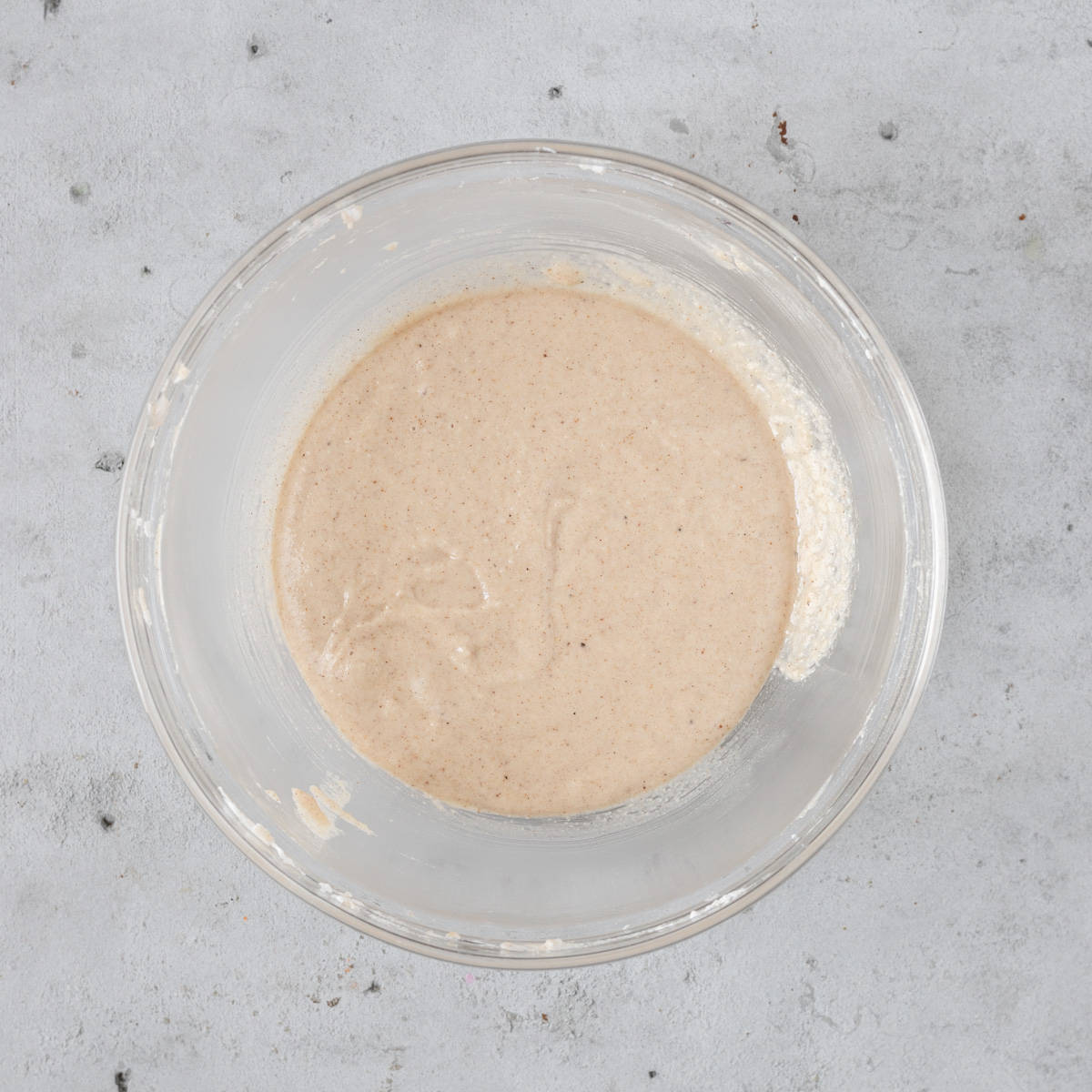 the macaron batter in a glass bowl on a grey background.