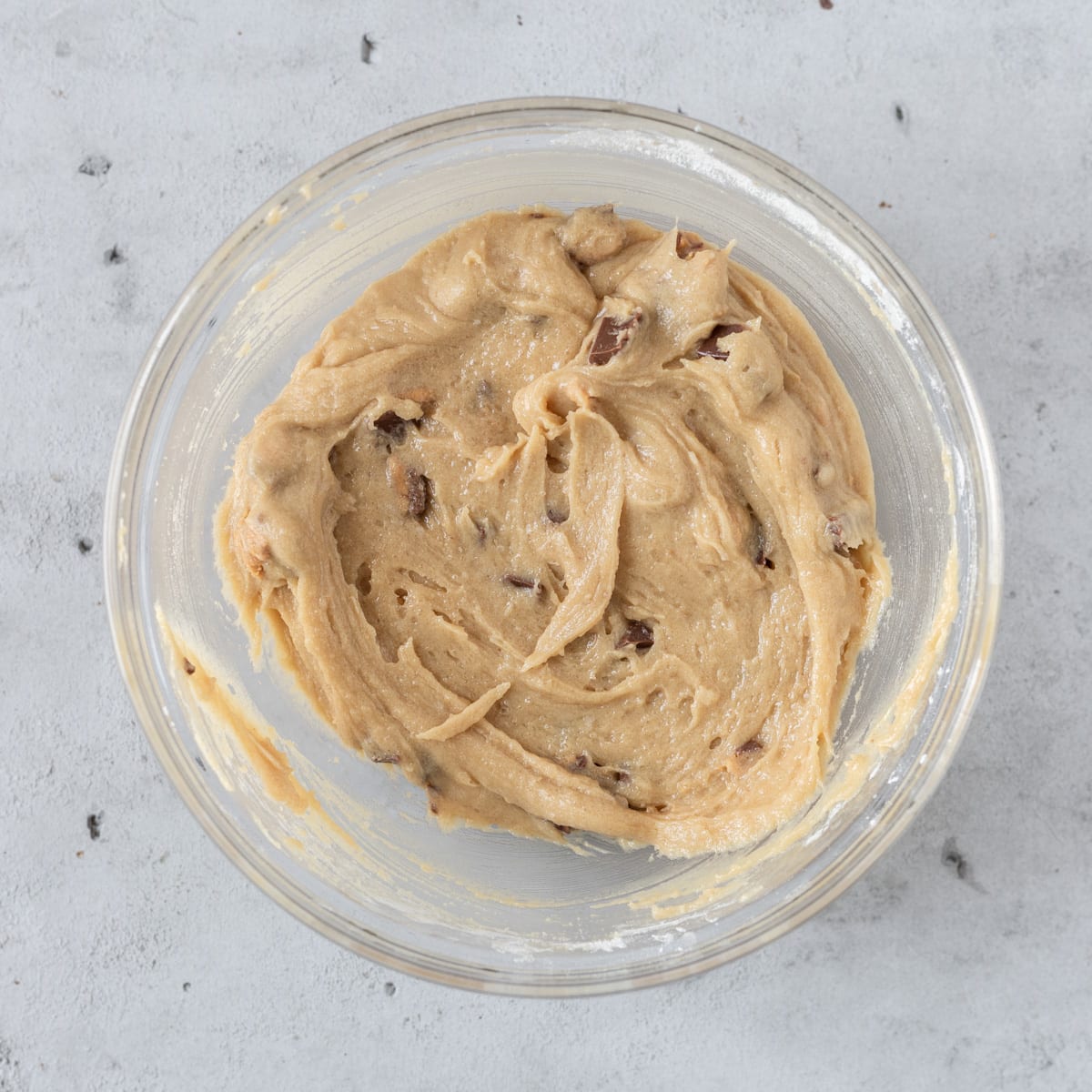 the completed cookie dough in a glass bowl on a grey background.