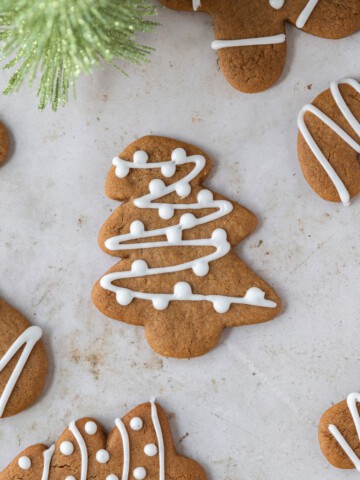 soft gingerbread cookies decorated with icing on a tan background.