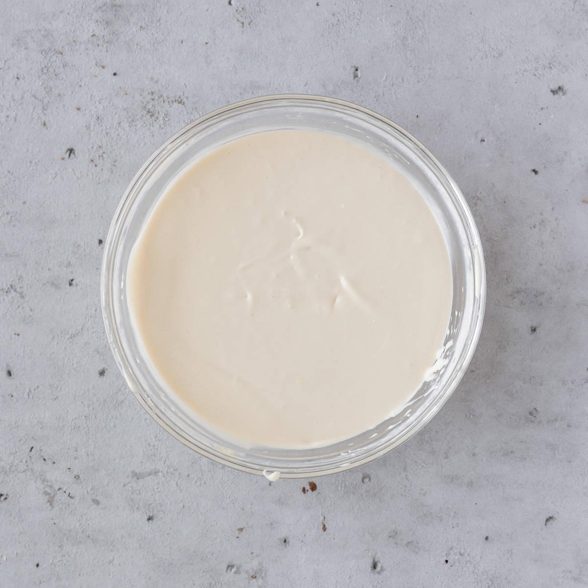 the vanilla cheesecake batter in a glass bowl on grey background.