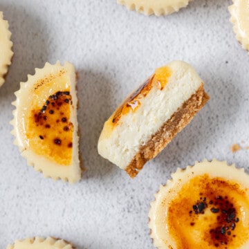 several mini creme brûlée cheesecakes on a grey background, one is cut in half.
