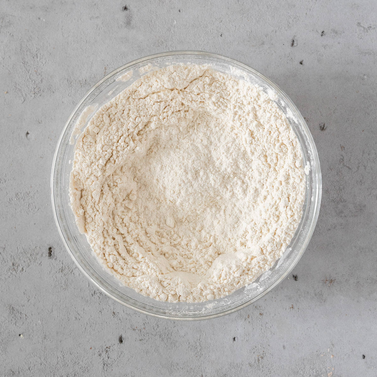 the dry ingredients combined in a glass bowl on a grey background.
