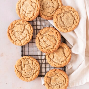 several almond flour peanut butter cookies spread out on a small wire rack with a linen napkin under it.