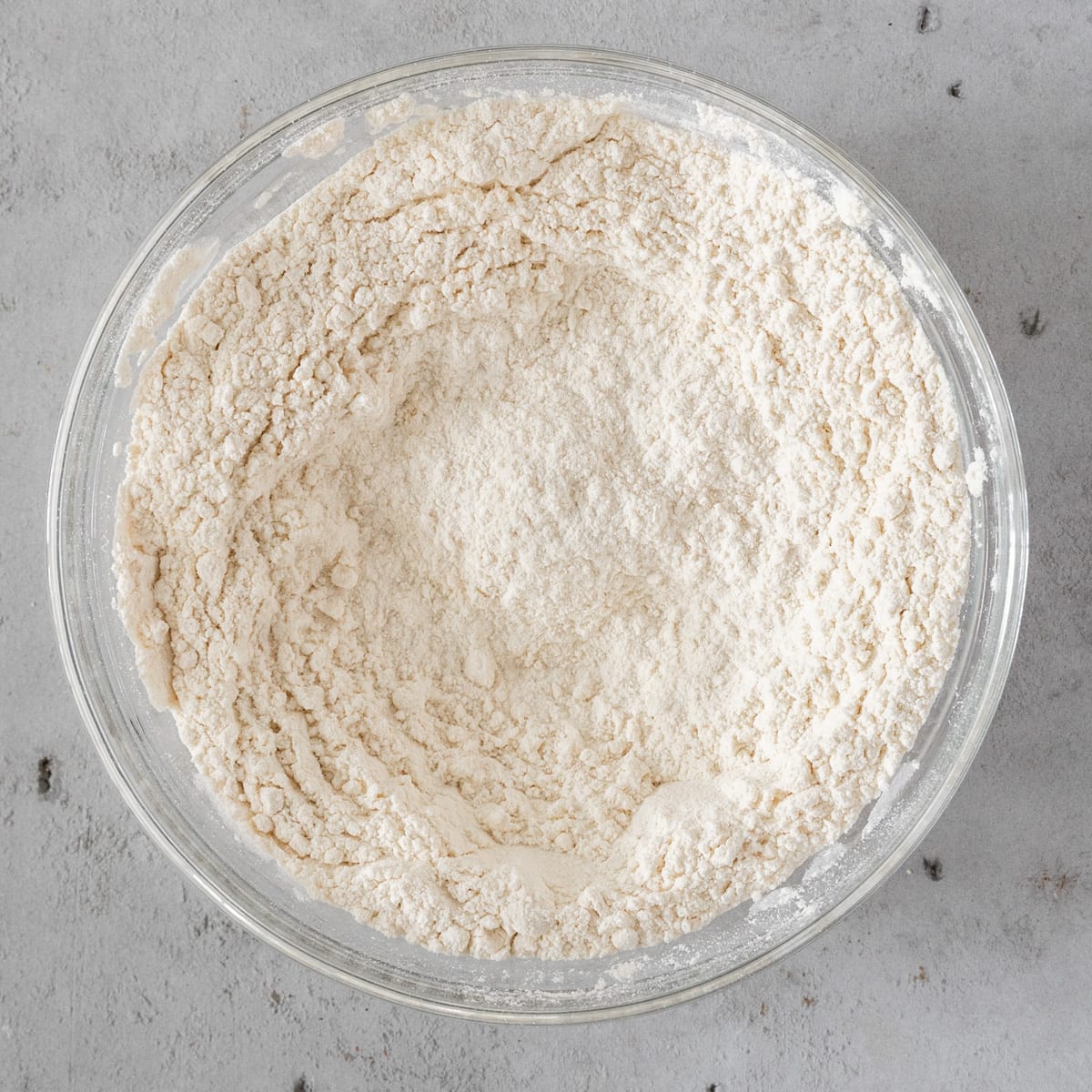 the dry ingredients combined in a glass bowl on a grey background.