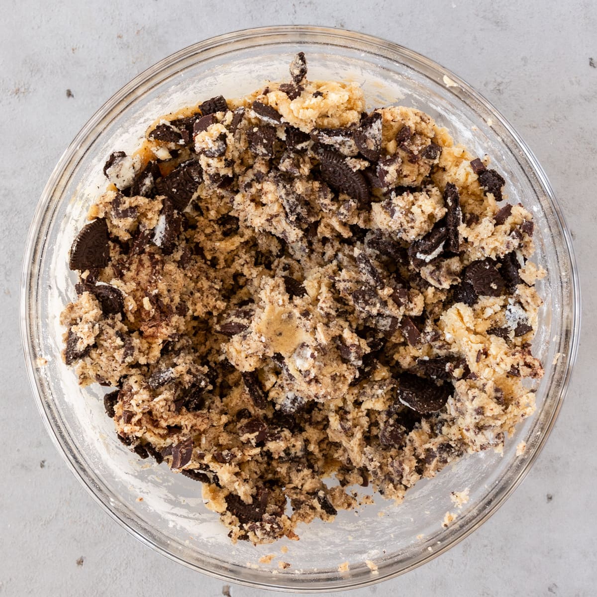 the completed cookie dough in a glass bowl on a grey background.