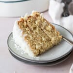 a slice of the coconut cake recipe on a two stacked grey plates with a fork next to it.