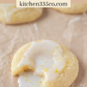 a lemony ricotta cookies with a bite out of it and icing spilling onto parchment paper. it says lemony ricotta cookies across the top.