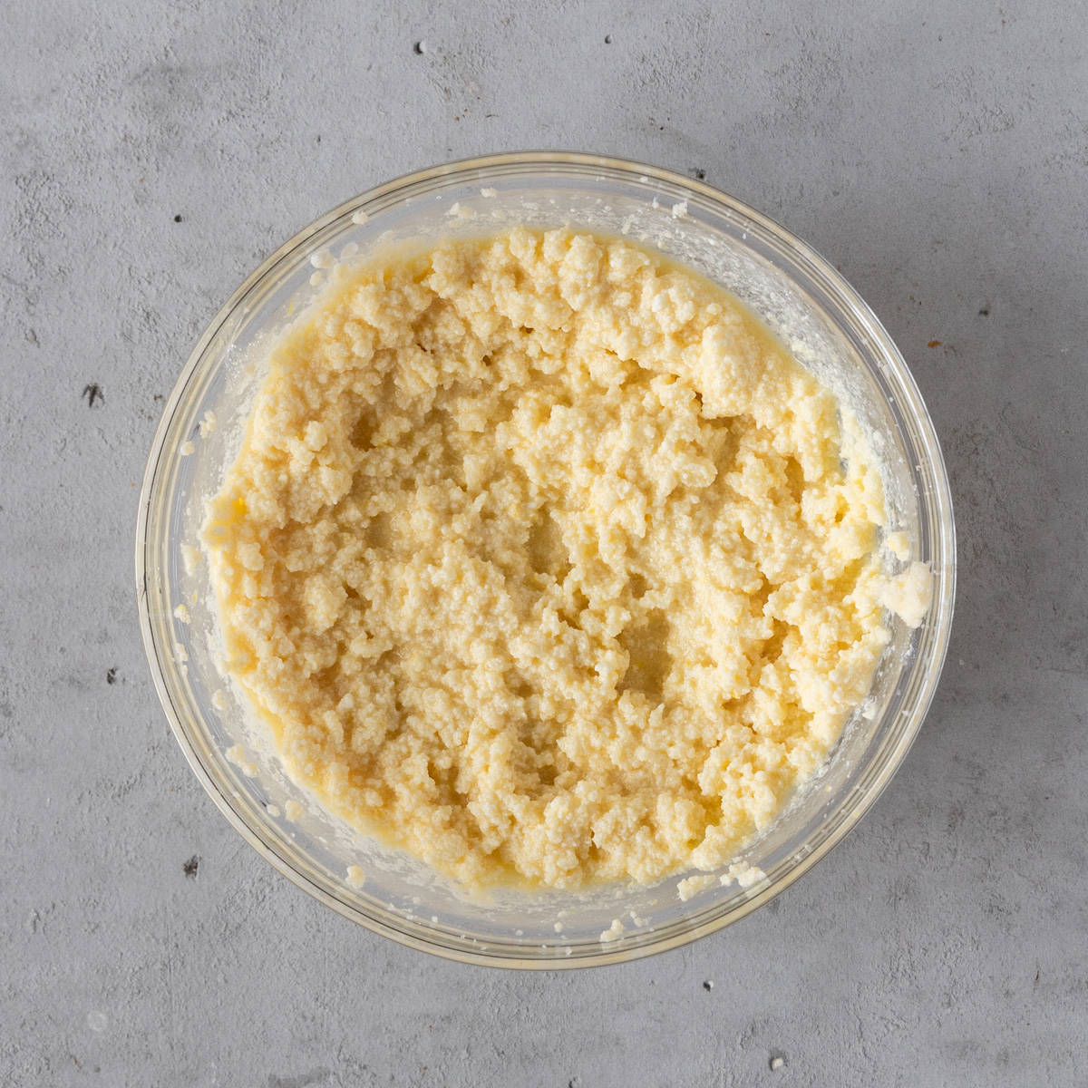 the wet ingredients and sugars combined in a glass bowl on a grey background.