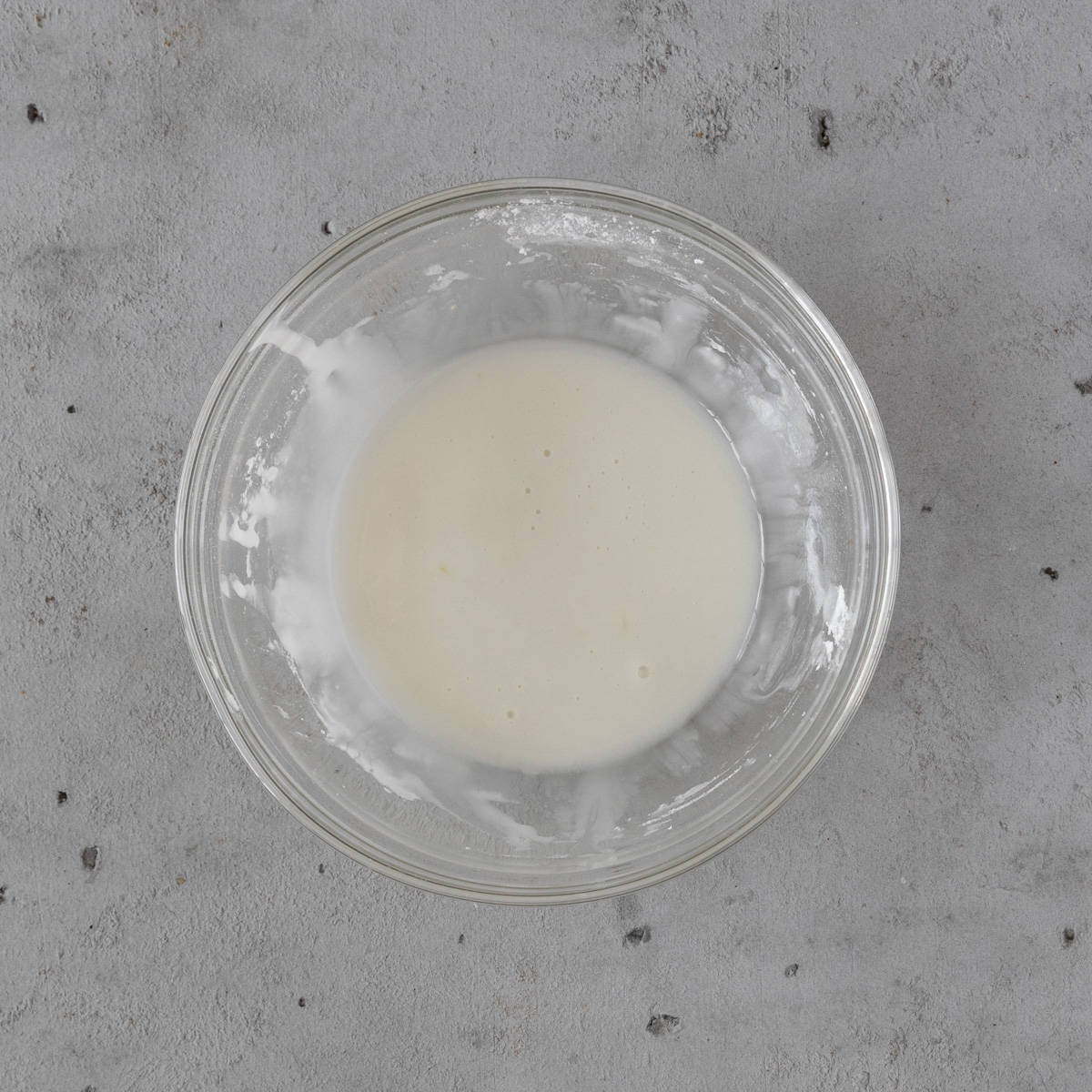 the lemon icing in a glass bowl on a grey background.