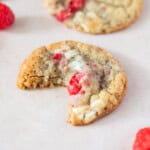 several raspberry and white chocolate and fresh raspberries, one has a bite out of it.