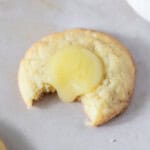 a lemon curd cookie with a bite out of it on a light background.