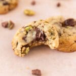 a pistachio cookie with a bite out of it leaning on another cookie.