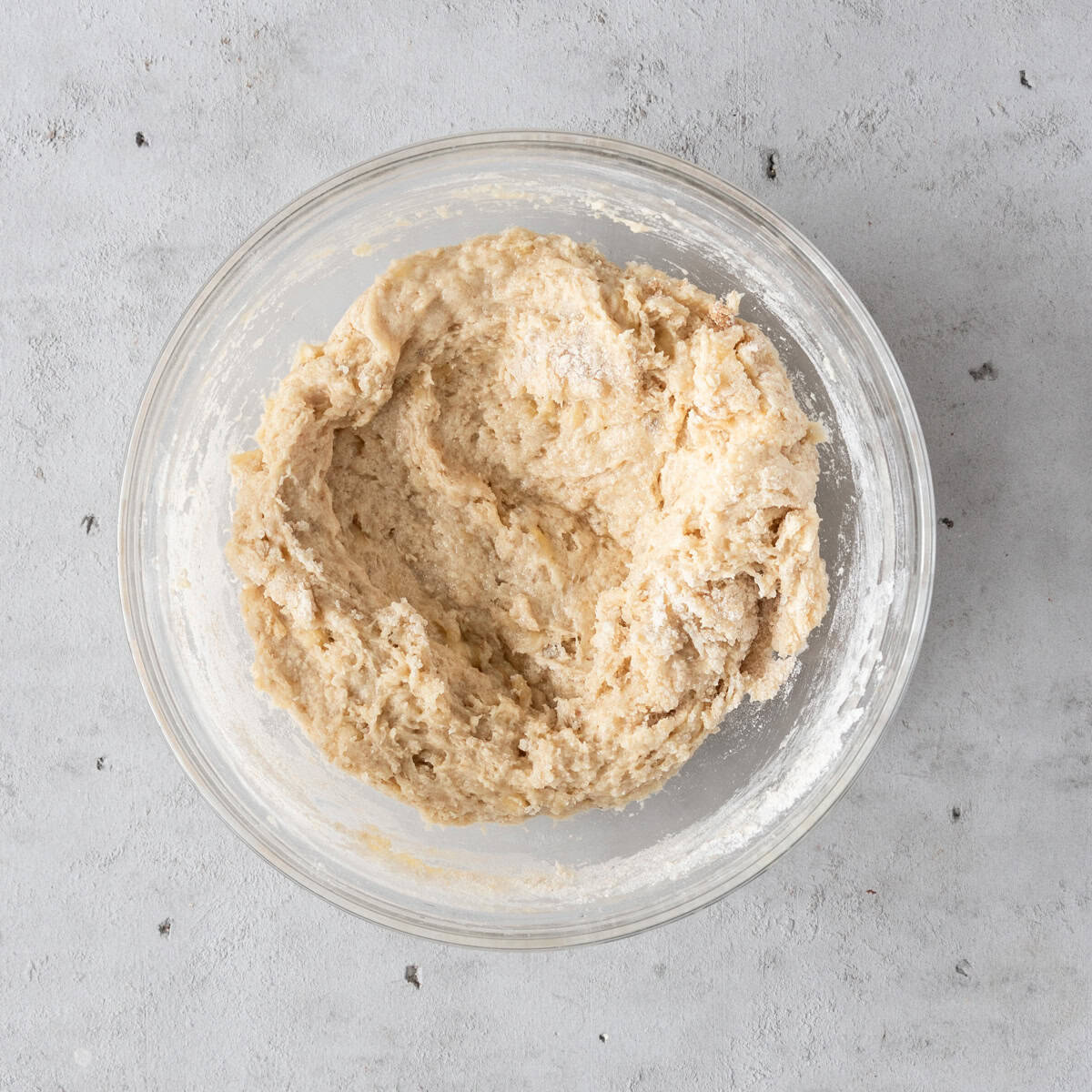 the wet and dry ingredients combined in a glass bowl on a grey background.