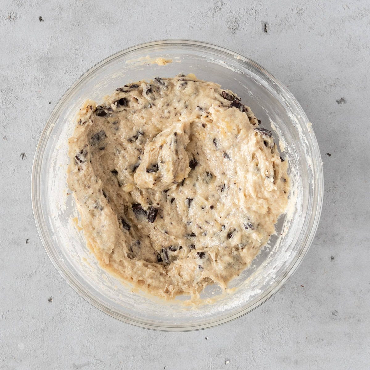 the completed muffin batter in a glass bowl on a grey background.