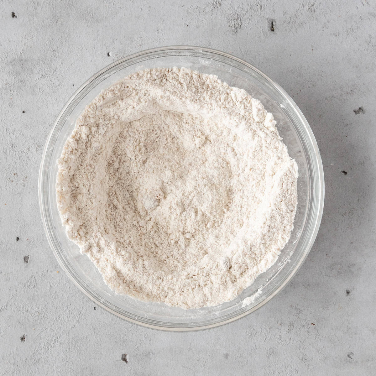 the dry ingredients combined in a glass bowl on a grey background.
