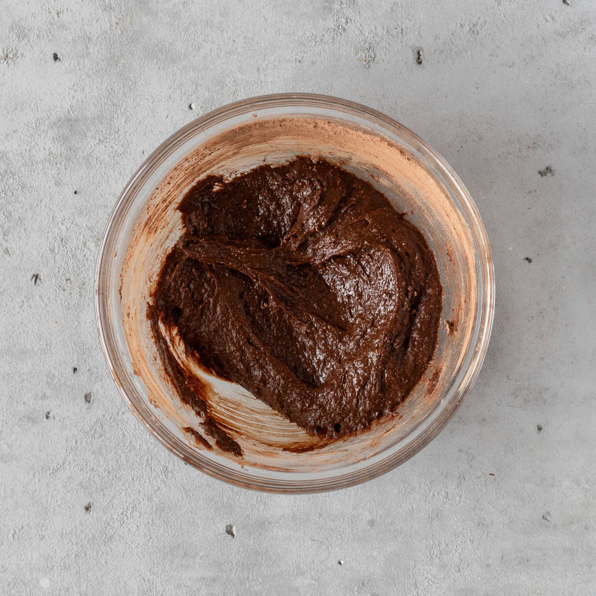 the wet and dry ingredients combined in a glass bowl on a grey background.