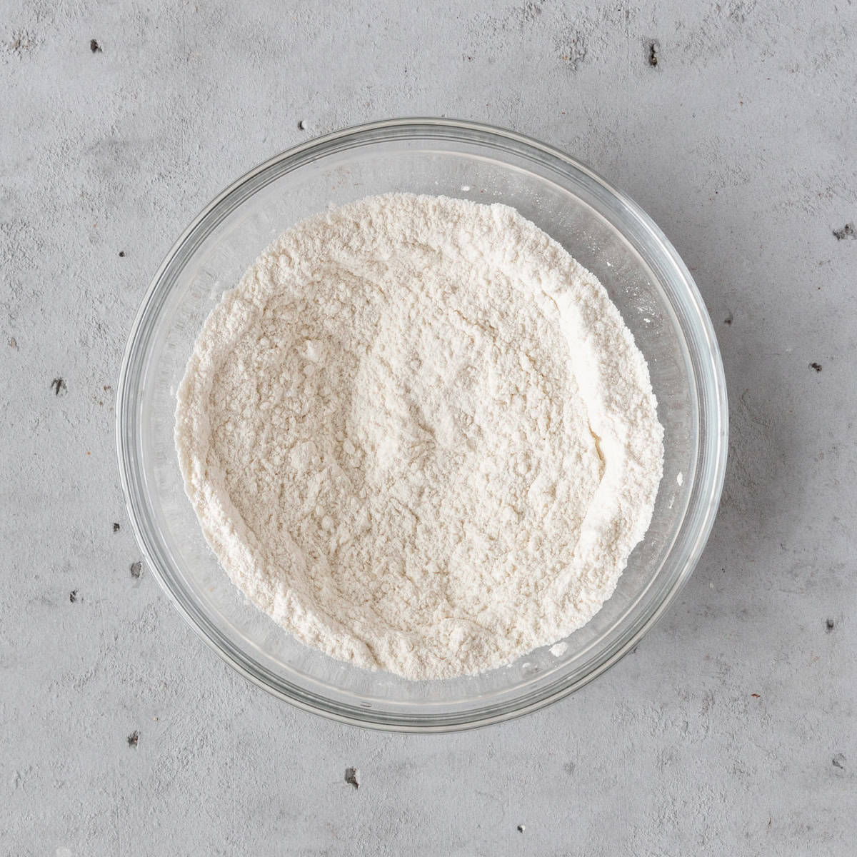 the dry ingredients combined in a glass bowl on a grey background.