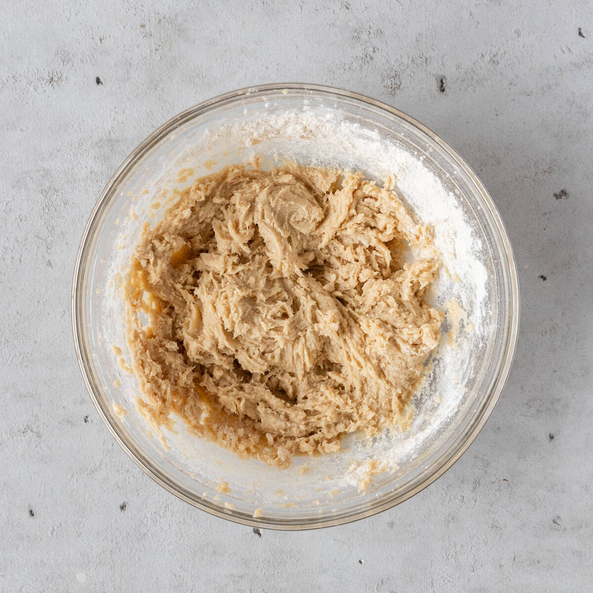 the wet and dry ingredients combined in a glass bowl on a grey background.