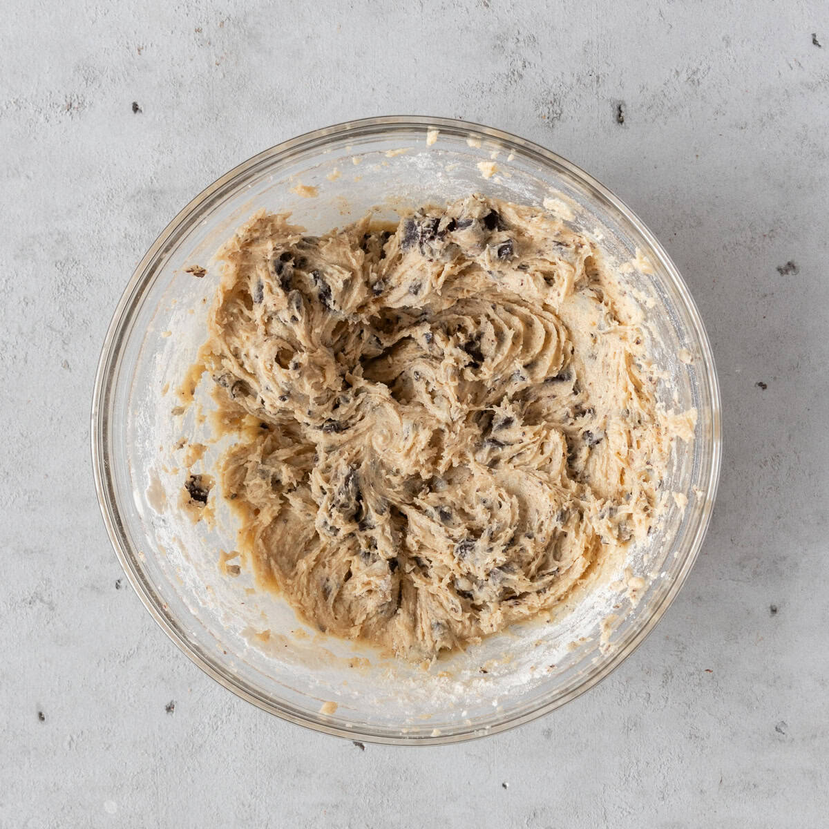 the completed cookie dough in a glass bowl on a grey background.
